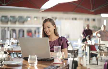 woman in purple shirt sitting by the table using macbook