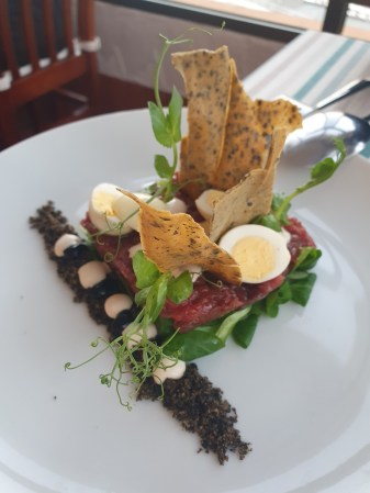 Beef tartare with Shimeji mushrooms in vinegar, quail egg, sand of capers and black olives, homemade anchovy mayonnaise and balsamic reduction at restaurant Que Bien © 2023 Live it up, Las Palmas!. All Rights Reserved.