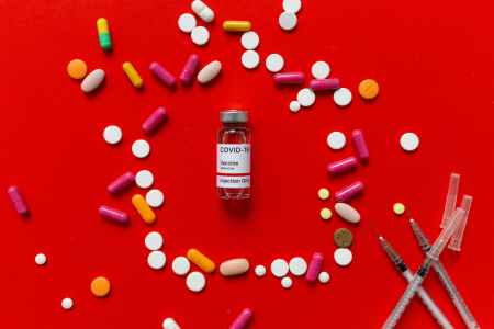 pills and a vial of vaccine